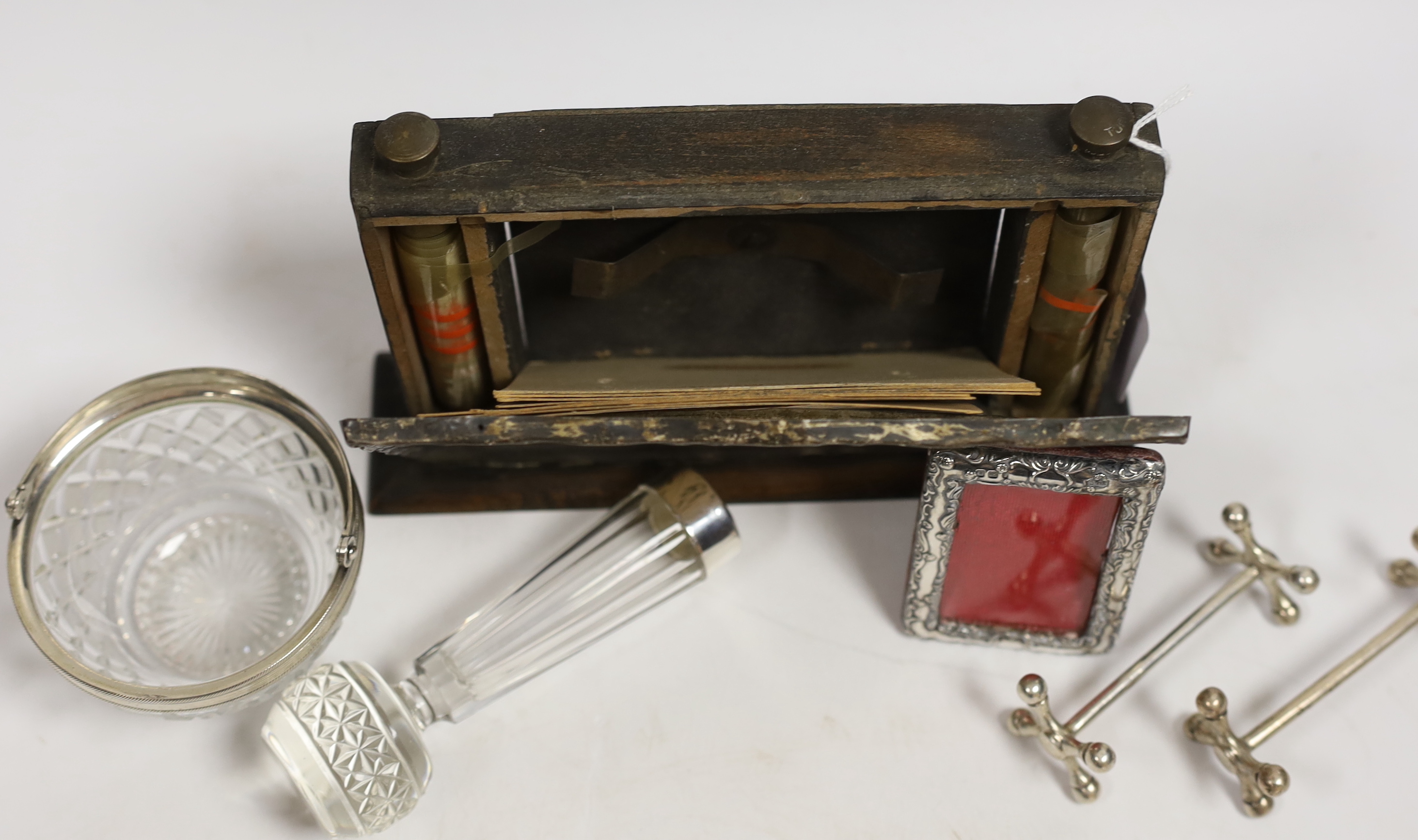 A pair of Edwardian silver knife rests, William Hutton & Sons, London, 1908, 77mm, a silver mounted wooden desk calendar, a late Victorian small silver mounted photograph frame, a silver mounted glass posy vase and a whi